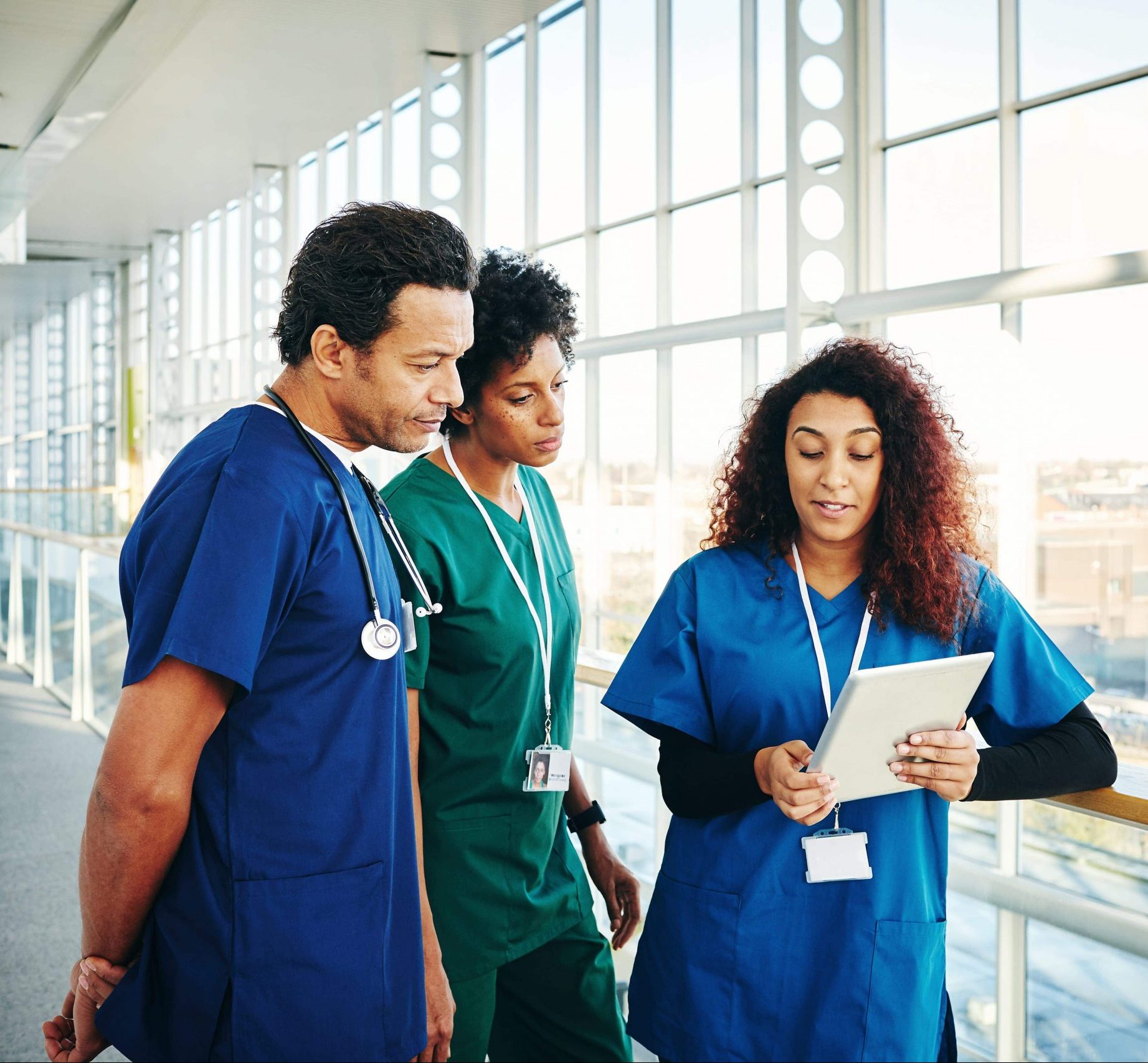 Surgeons discussing over digital tablet in hospital corridor