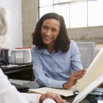 Smiling female analyst in consultation with senior woman