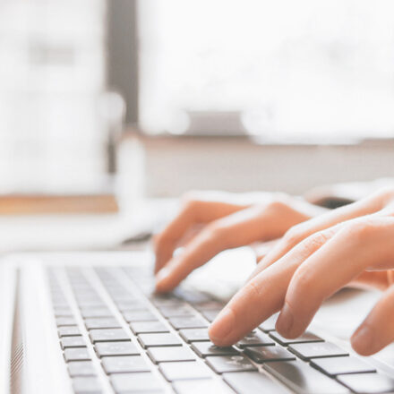 Distance education. Online college training. Remote student learning. Closeup of hands typing on laptop.