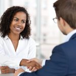 Smiling african female hr manager handshake hire male candidate at job interview make good first impression, happy mixed race client shake hand of bank broker, respect, business agreement concept