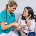 Shot of a young doctor holding a tablet and talking to her patient. Health visitor and a senior woman with tablet. Shot of female nurse and senior woman using digital tablet together